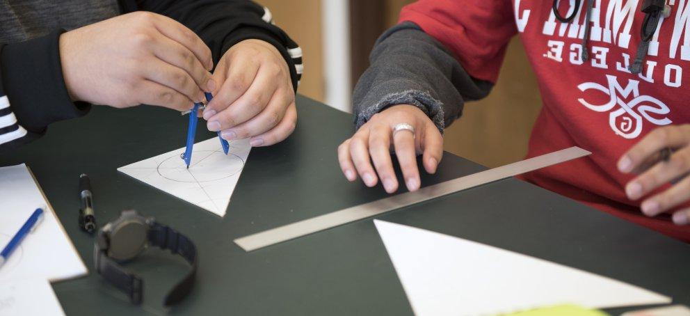 Two students using a ruler and protractor to accomplish math